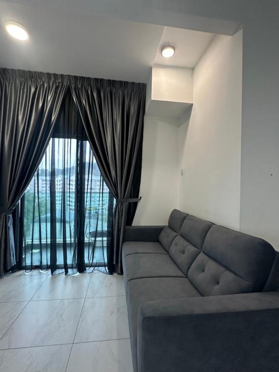 un soggiorno con un divano e una grande finestra di Adik Aisyah cameron homestay quintet A3-7-7 a Tanah Rata