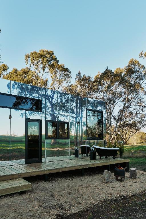 a glass house with a table and a bench at Nestled Cabins in Verdun