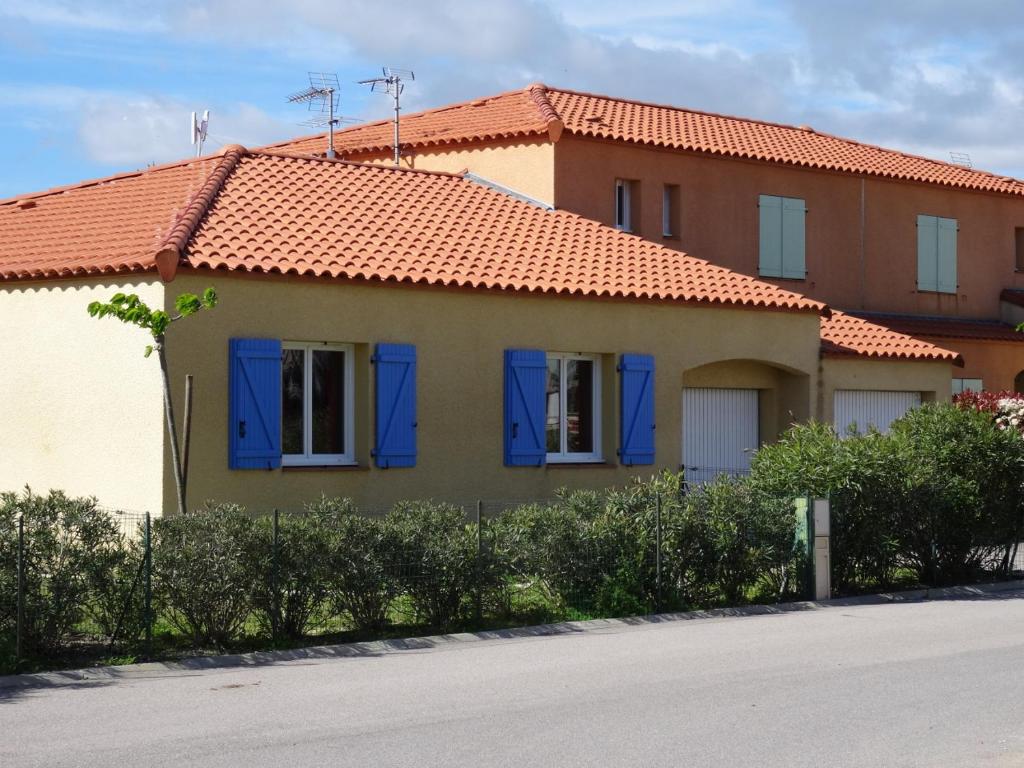 a house with blue shutters on a street at Villa 8 De Oranje Tulp in Le Barcarès