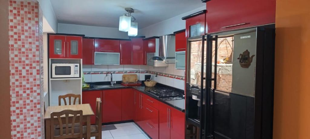 eine rote Küche mit roten Schränken und einem schwarzen Kühlschrank in der Unterkunft depahuarazhermoso in Huaraz