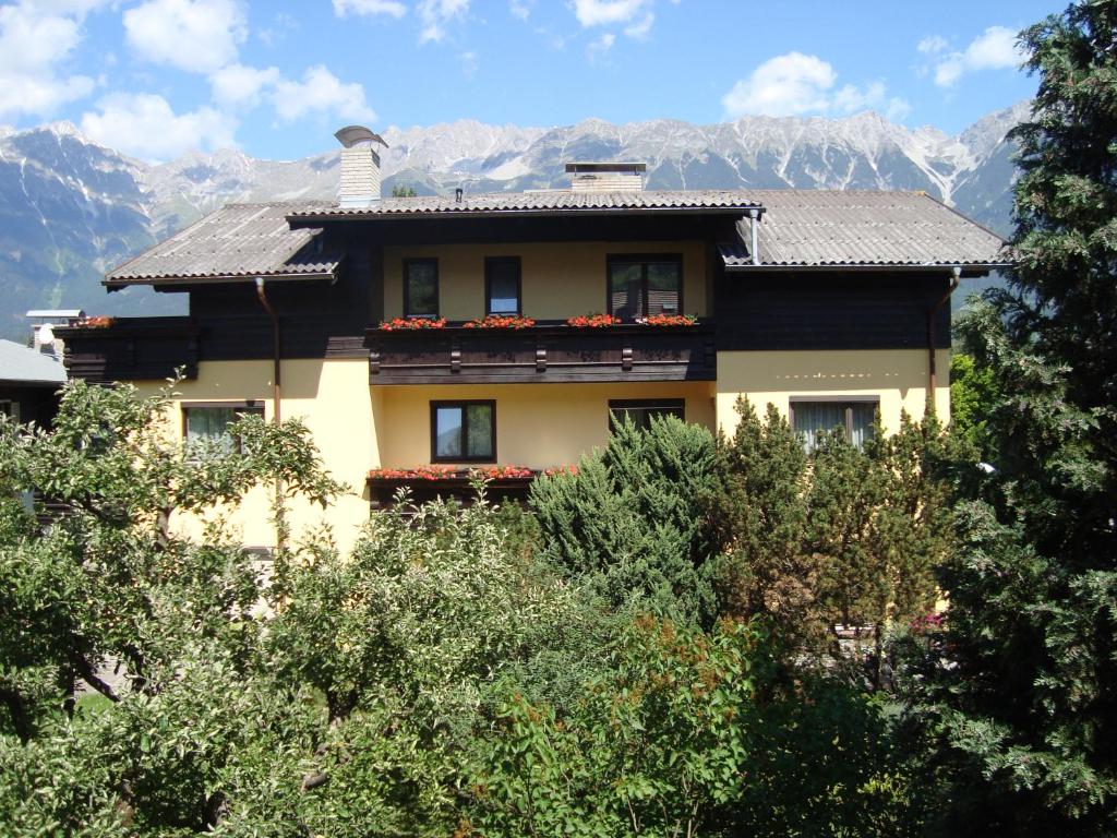 a house with flowers on the balcony in front of mountains at Pension Friedl in Innsbruck