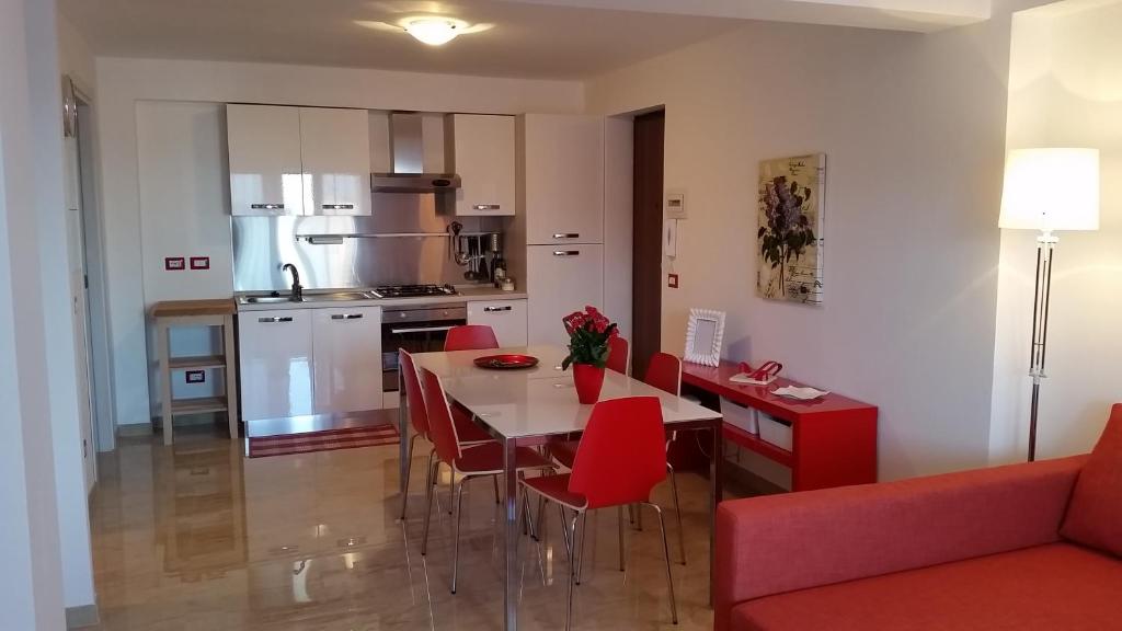 a kitchen and living room with a table and red chairs at Baia Giardini Apartments in Giardini Naxos