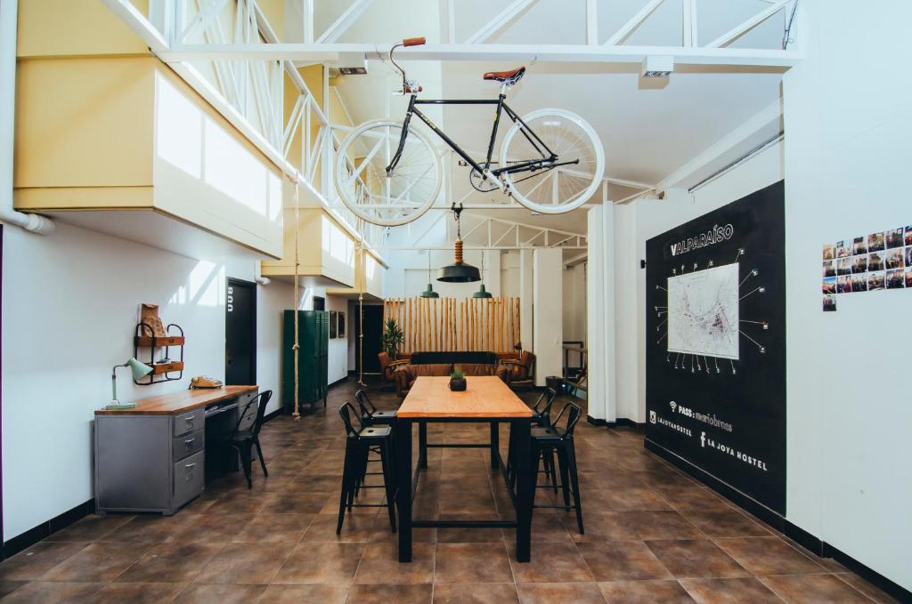 uma bicicleta pendurada no tecto numa sala com uma mesa em La Joya Hostel em Valparaíso