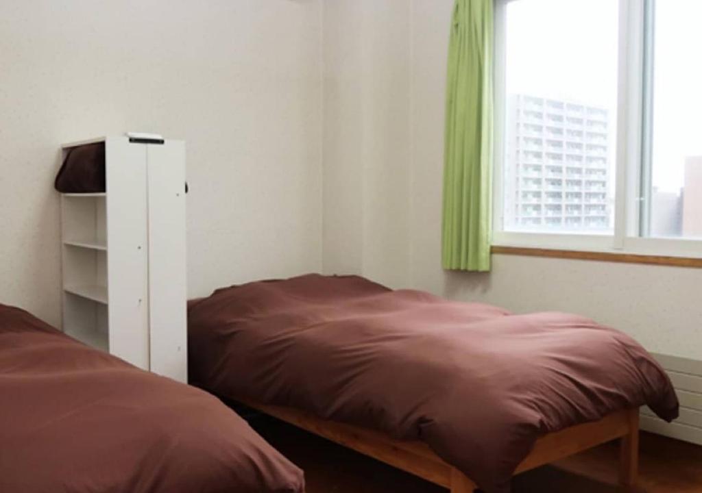 a bedroom with a bed and a window with green curtains at Kamome Building 3F - Vacation STAY 50189v in Otaru