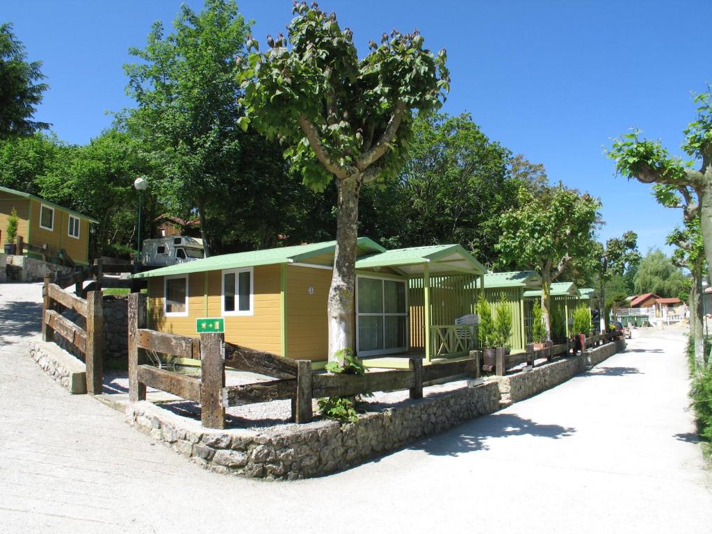 un camping con un árbol y una valla en Camping Rio Purón en Llanes