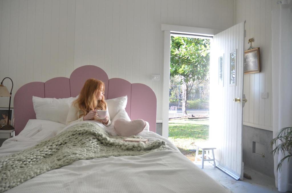Una ragazza seduta su un letto che legge un libro di The Dairy at Cambewarra Estate Winery a Camberwarra