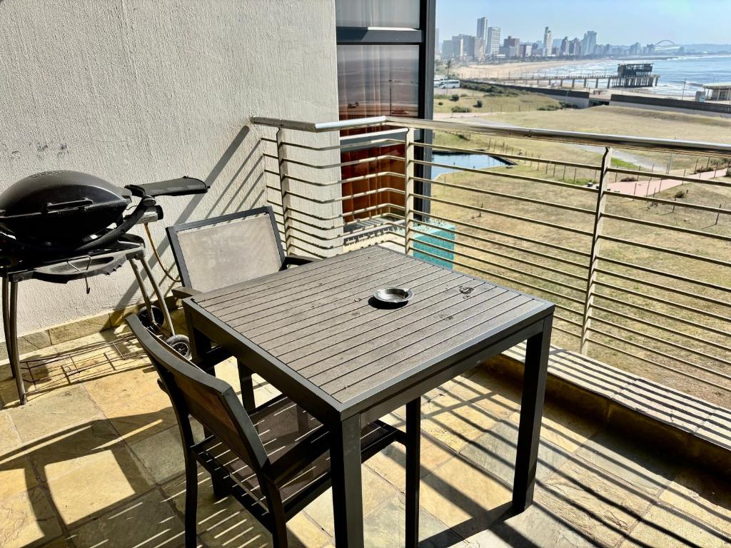 a table and chair on a balcony with a grill at Durban Point Waterfront, 505 Quayside 40 Canalquay Rd in Durban
