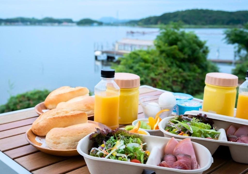 una mesa con platos de comida y botellas de zumo de naranja en Glamping Base IZUMO "Lakeside Hot Spring Hotel Kun - Vacation STAY 42021v, en Izumo