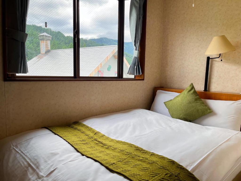 a bedroom with a white bed with a window at Yuzawa Hotel New Fukudaya-ski in ski out in Minami Uonuma