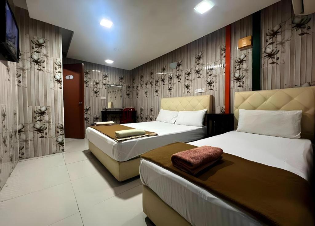 a hotel room with two beds and a couch at Shah Alam Business Hotel in Kampong Melayu Kebun Bunga
