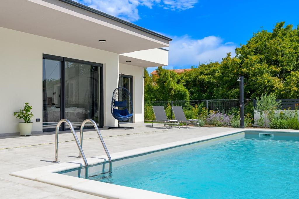 une piscine avec deux chaises à côté d'une maison dans l'établissement Villa Lamia by IstriaLux, à Burići