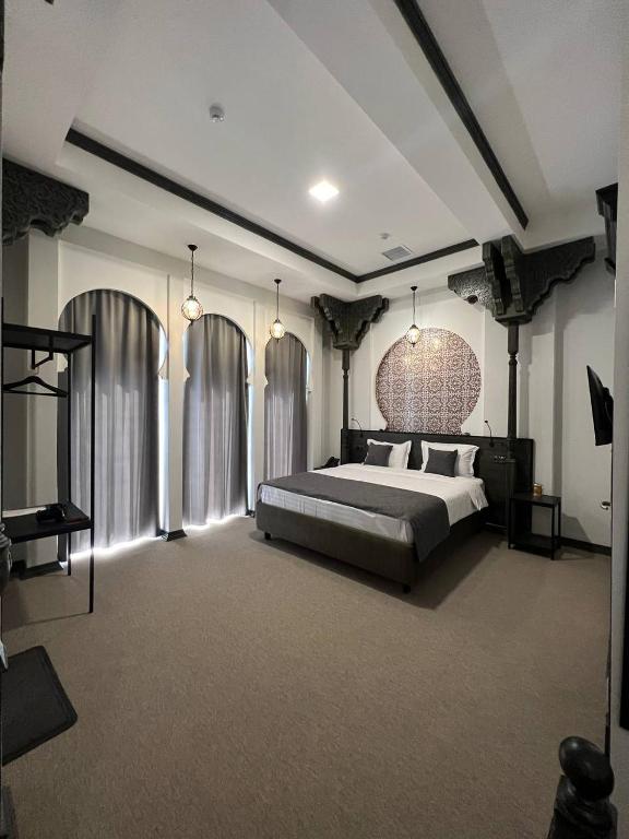 a bedroom with a large bed and a large room with windows at Rasoda Hotel&Restaurant in Tashkent