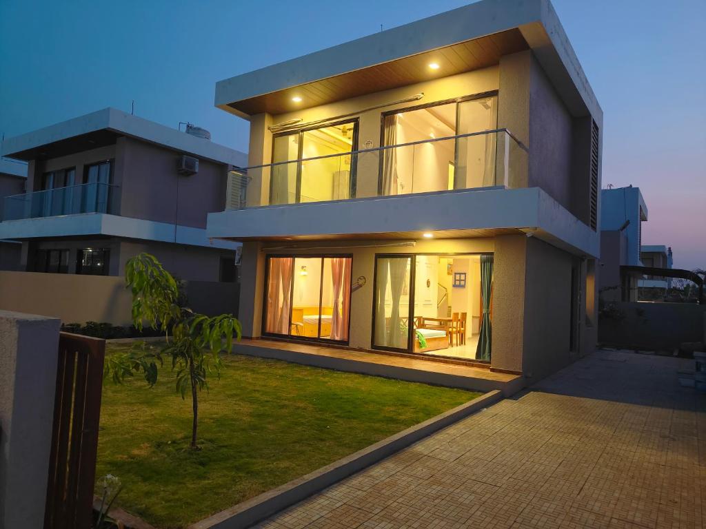 a large house with lights on the side of it at Cozy 3BHK Villa with a Private Lawn - Karjat in Dhamni
