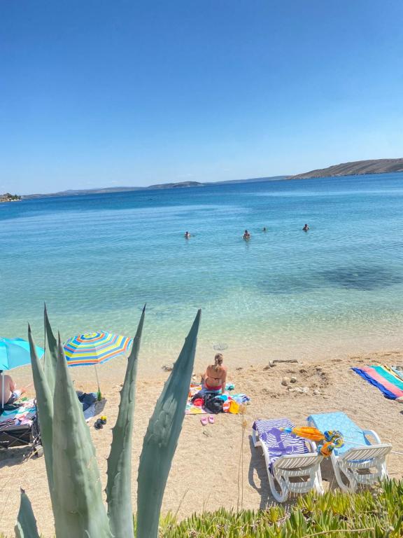 a beach with chairs and people in the water at Sea View Apartments Nini in Vlašići
