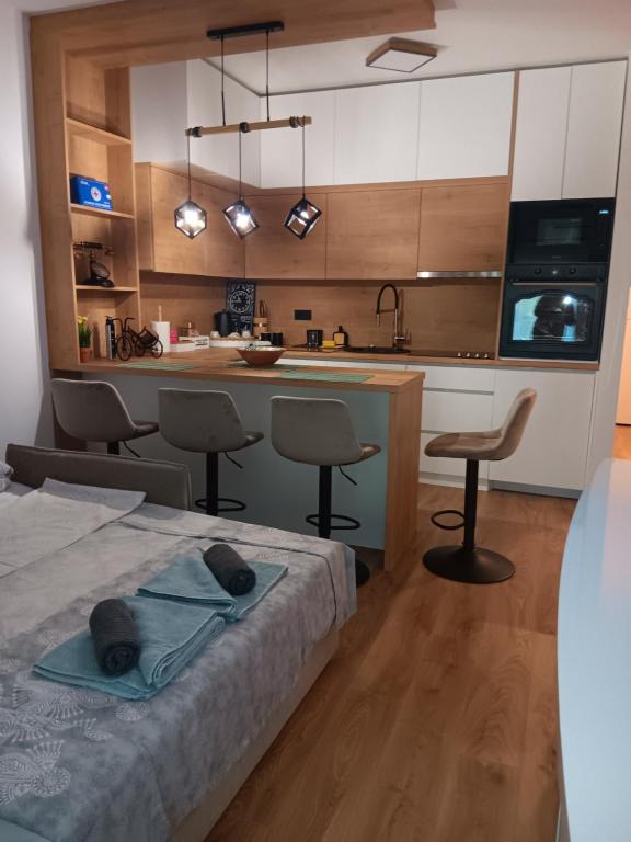 a bedroom with a bed and a kitchen with chairs at Studio apartman Hušnjakovo Hill in Krapina