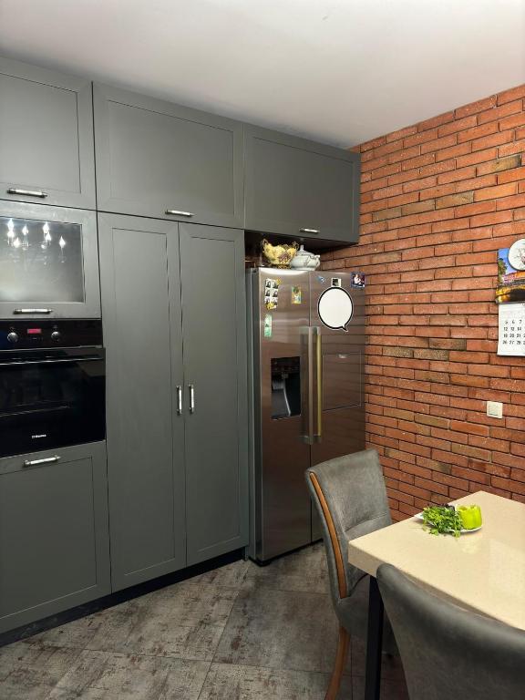 a kitchen with gray cabinets and a brick wall at Charming Private House Pekini av in Tbilisi City