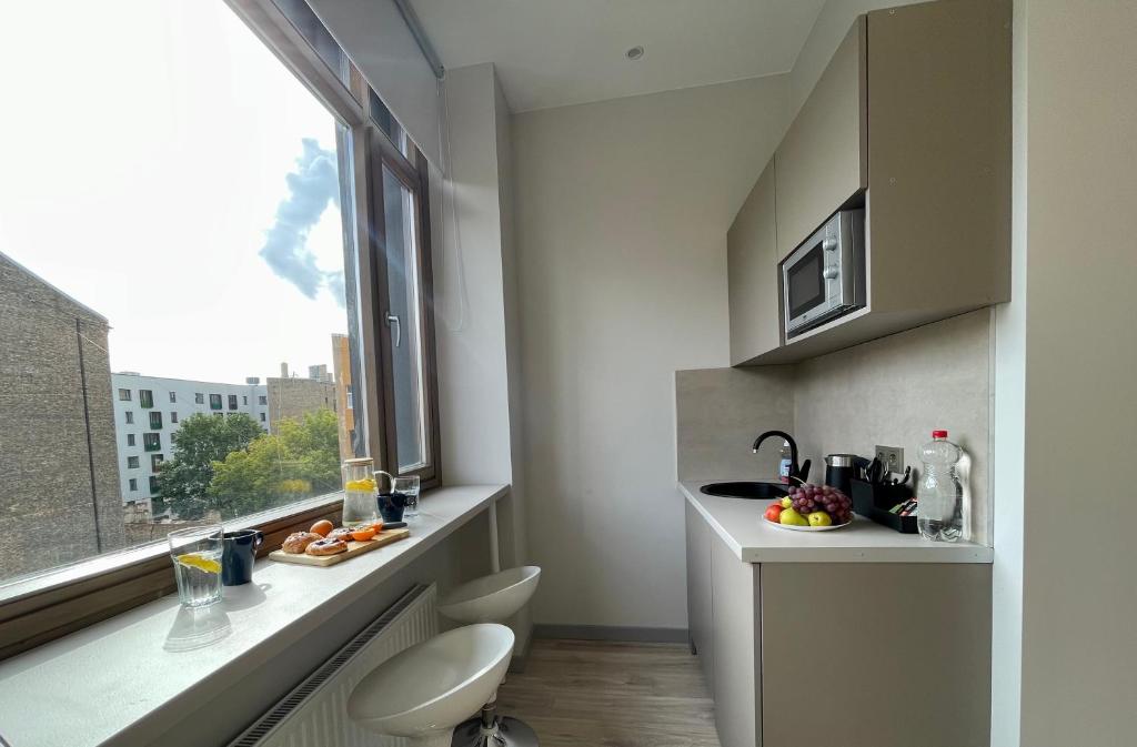 Cozinha compacta do Aparthotel Aurum com armários brancos, bancada cinza e mesa redonda com flores