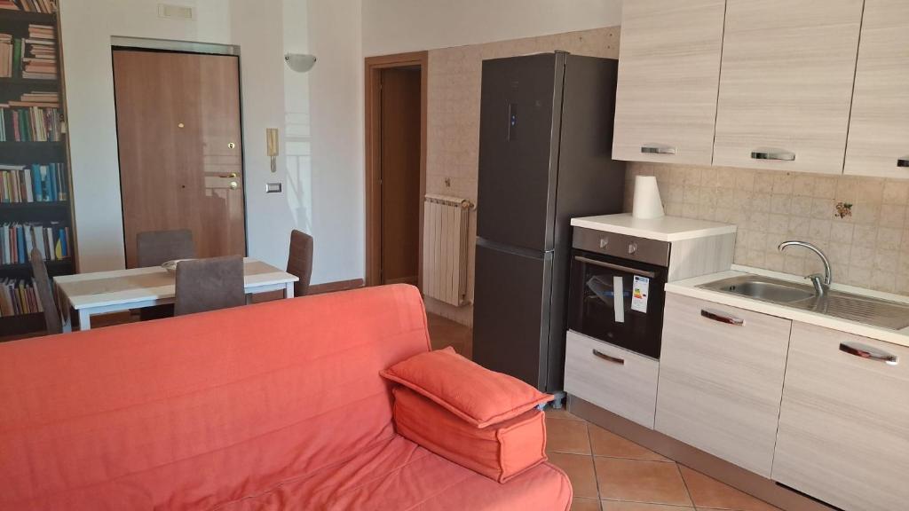 a living room with a red couch and a kitchen at Bilocale nei pressi dell'Aeroporto in Pontecagnano