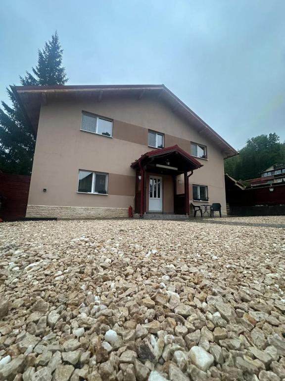 a house with a large stone ground in front of it at Azuga Home in Azuga