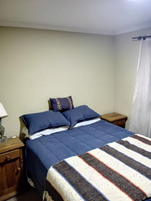 a bedroom with a blue bed with blue pillows at Alojamiento Solar Las Rastras in Talca