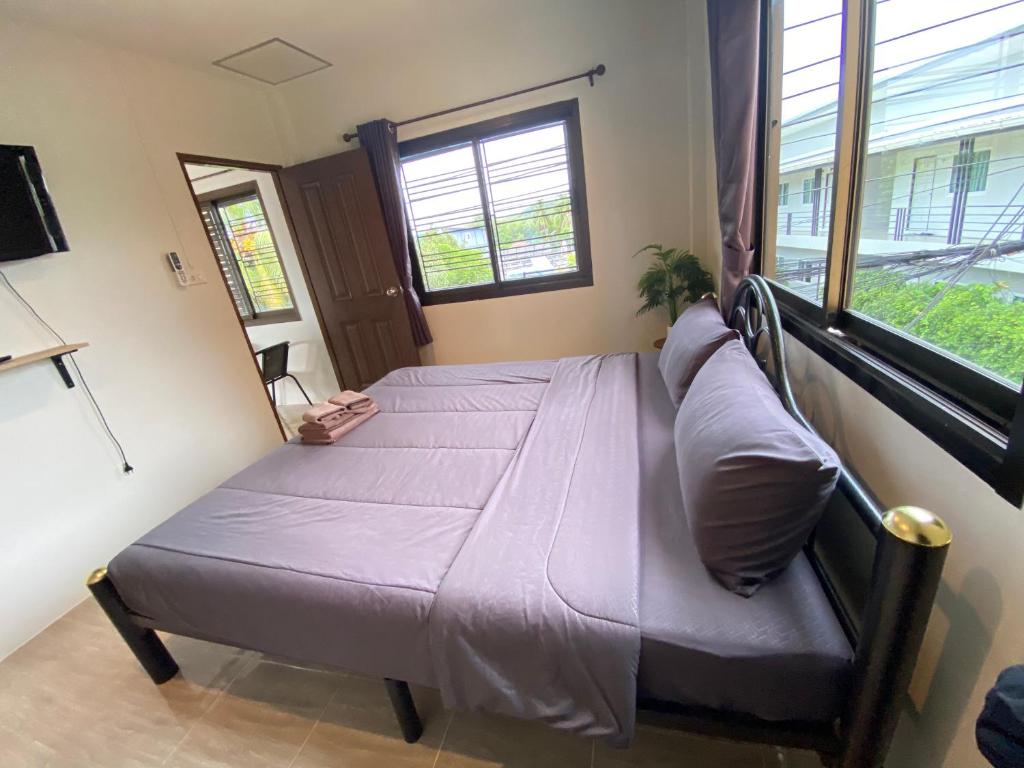 Un dormitorio con una cama con sábanas moradas y una ventana. en Fran Sim Da Guest House, en Bang Tao Beach