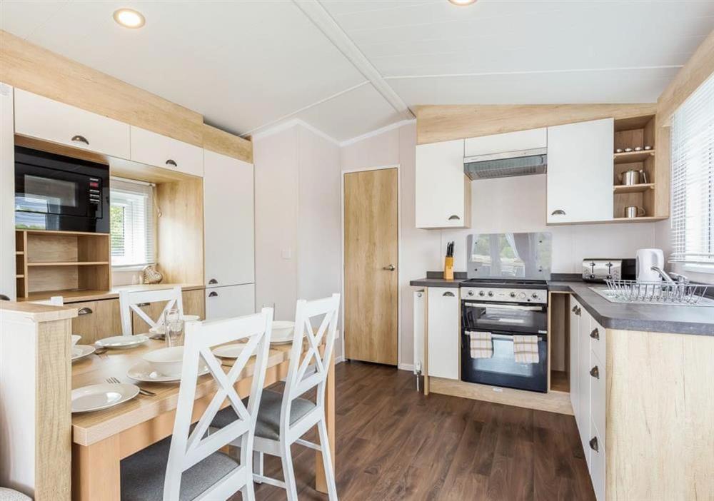 Una cocina con gabinetes blancos y una mesa y sillas. en Sanctuary 10 Hot tub lodge, en Fort Augustus