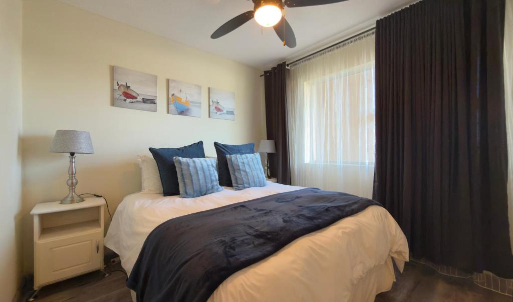 1 dormitorio con 1 cama con almohadas azules y ventilador de techo en Stylish stay at Hartensee, en Mossel Bay