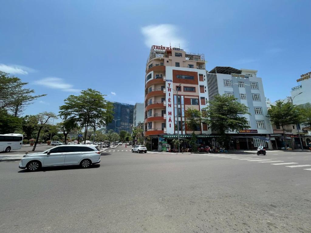 a white car driving down a city street with a building at Khách sạn Đông Tây Quy Nhơn in Quy Nhon