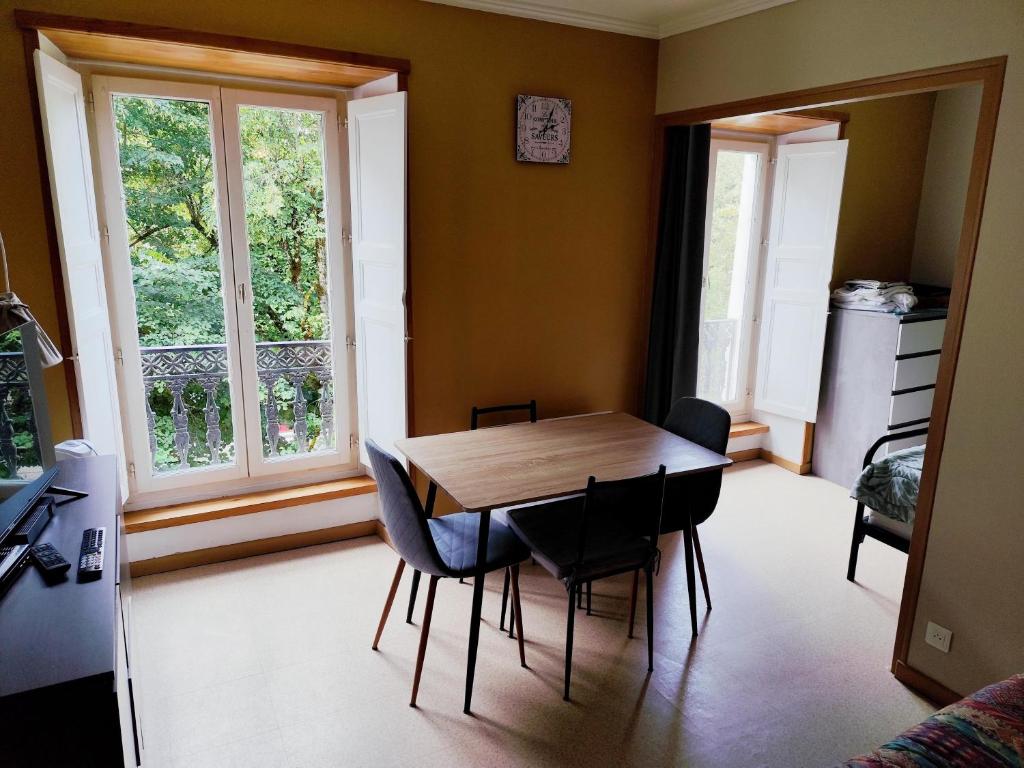 a dining room with a table and chairs and a window at appartement T1 hyper centre 350 m des thermes 200 m des télécabines deuxième étage avec ascenseur in Luchon