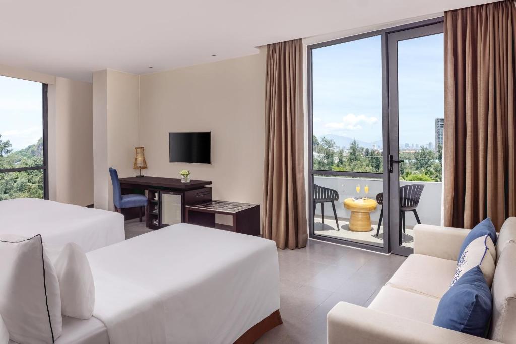 A two-bed room with a furnished balcony, a sofa and a green-and-city outlook.