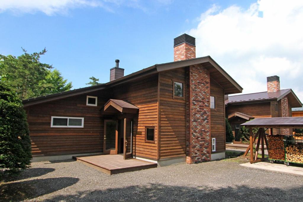 a wooden house with a porch and a building at Kitakaruizawa Sweet Grass - Vacation STAY 61669v in Kita-karuizawa