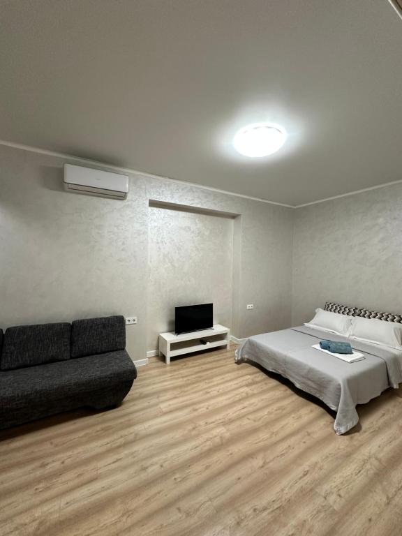 a bedroom with a bed and a couch and a tv at Квартира на Торайгырова in Almaty