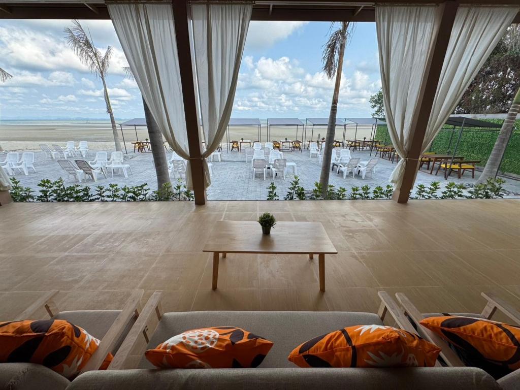 Una sala de estar con sillas y una mesa y una vista a la playa. en De Mer Resort Rayong, en Ban Ao Makham Pom