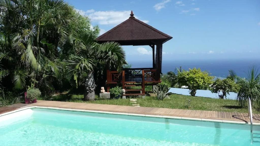 a swimming pool with a gazebo next to the ocean at Appartement convivial avec vue sur la mer in Les Avirons