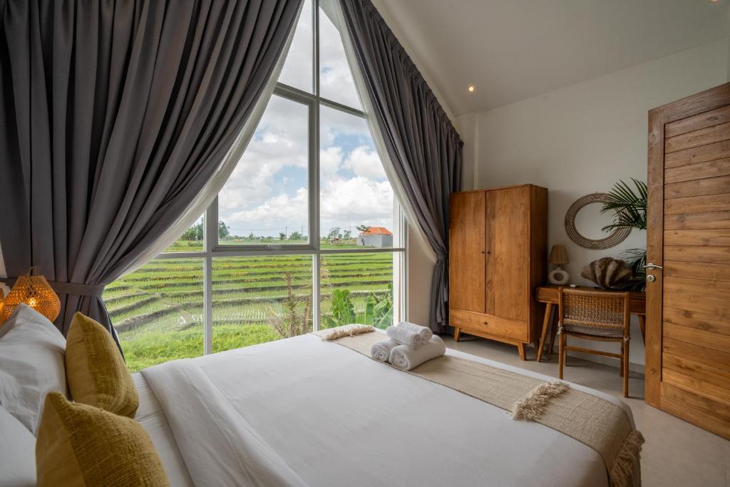 a bedroom with a bed with a large window at Sunrise Bliss 15 Ricefield View Private Pool Villa By Bali Bliss Properties in Dalung