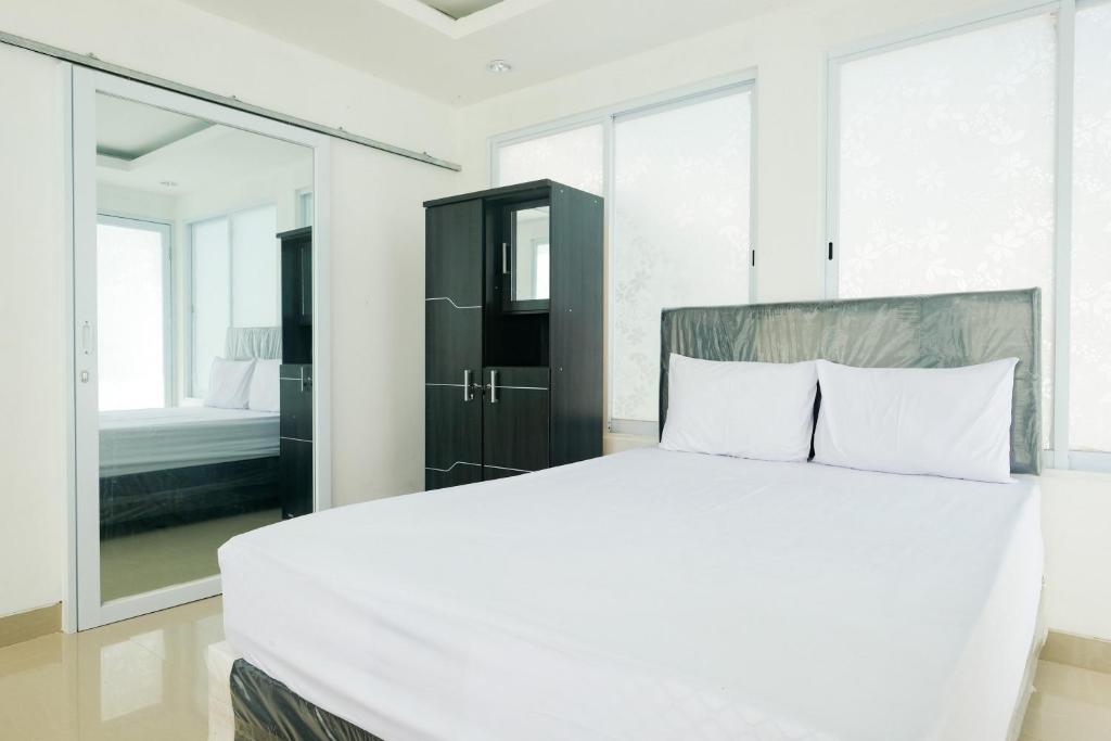 a white bedroom with a large bed and a mirror at David Houses Nusa Dua Beach Bali RedPartner in Nusa Dua