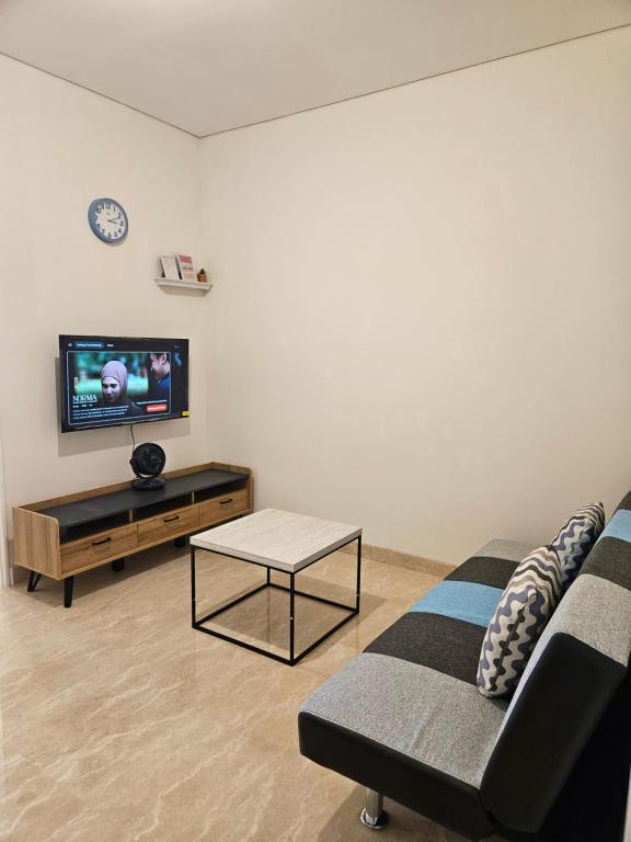 a living room with a couch and a tv at Premium Apartment Podomoro 1 Bedroom with Best Garden & City View in Medan