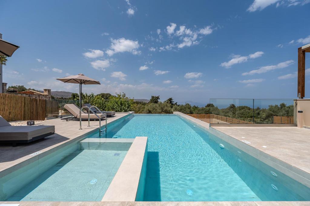 a swimming pool with an umbrella next to a house at Athos Rural Villa in Prinés
