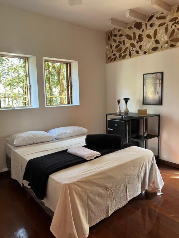a bedroom with a large bed and two windows at Hari Eco Pousada in Brumadinho