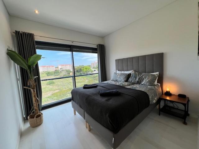 a bedroom with a bed and a large window at Cavalo Branco Portugal in Quarteira