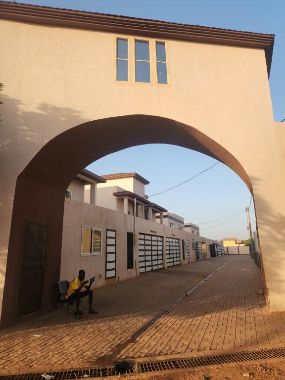 a person sitting on a bench under a building at Résidence AMIRAL in Niamey