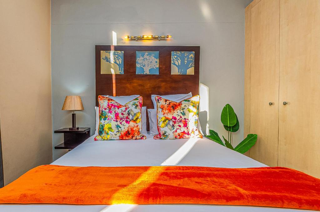 ヨハネスブルグにあるRustic Oasis at Mapungubwe 4 Star Hotel, Johannesburgのベッドルーム(大きな白いベッド、カラフルな枕付)