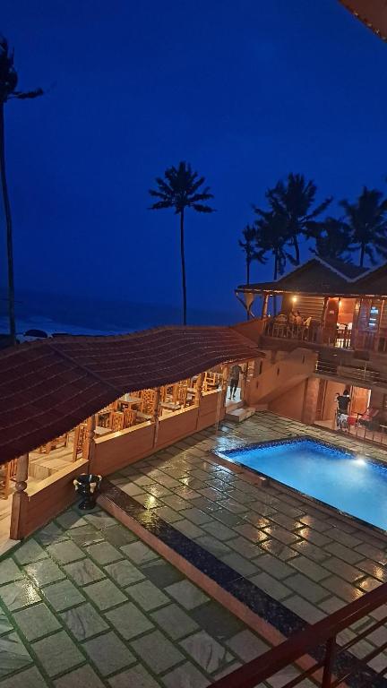 a resort with a swimming pool at night at Bella Casa Beach Resort in Varkala