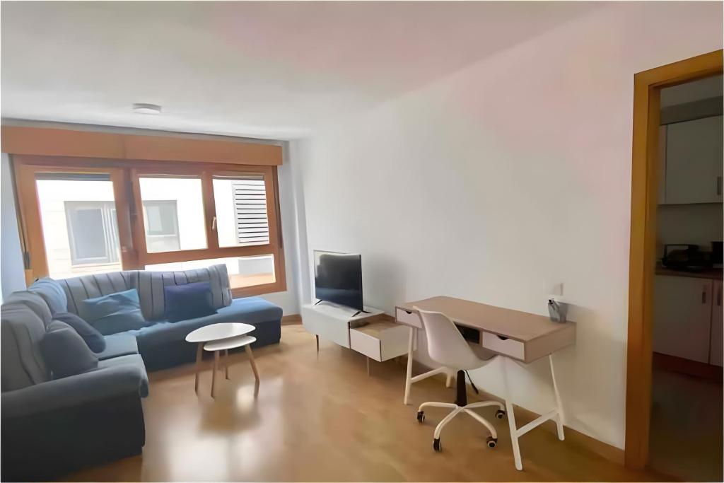 ein Wohnzimmer mit einem blauen Sofa und einem Schreibtisch in der Unterkunft Attenery in Las Palmas de Gran Canaria