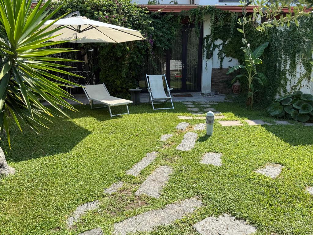 a yard with two chairs and an umbrella at Casagiardino Sofía in Marina di Varcaturo