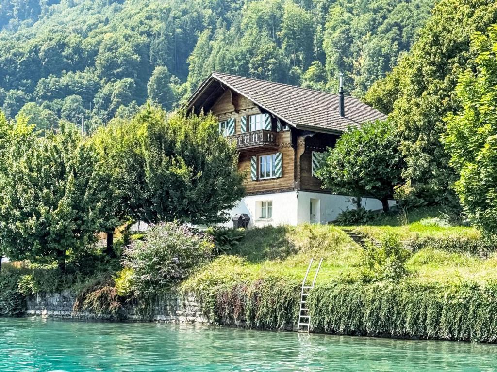 a house on a hill next to a river at Chalet Haus am See 4B by Interhome in Niederried