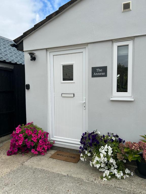 una casa bianca con una porta e dei fiori di The Annexe Long Melford a Long Melford