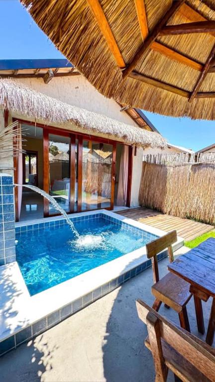 a swimming pool with a table and an umbrella at Chalés Milagres Beach in São Miguel dos Milagres