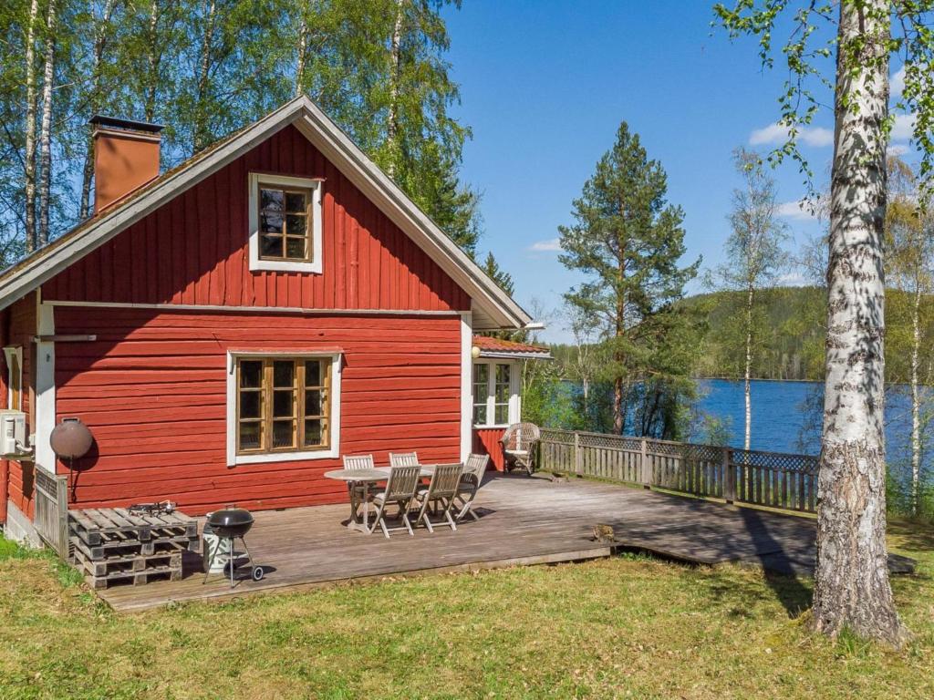 een rode hut met een terras naast een meer bij Holiday Home Koivikko by Interhome 