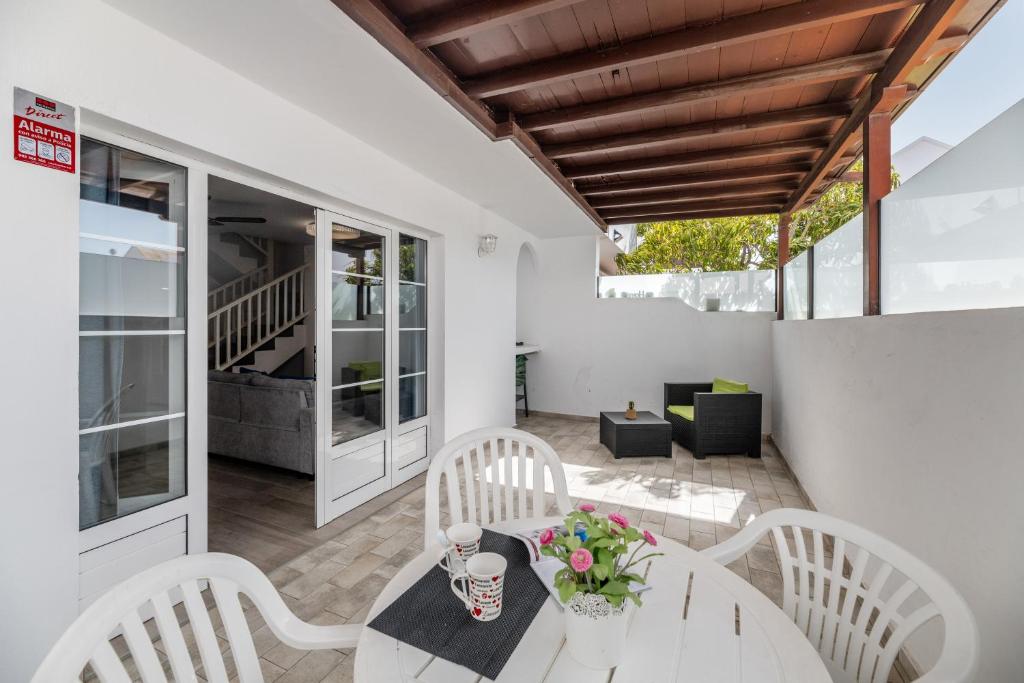 un patio con sillas blancas y una mesa con flores. en Casa Melani, Sea and Relax, en Playa Honda